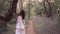 Cute young girl in a white transparent long dress with a floral pattern and dark wavy hair was captured by the spirit of