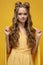 Cute young girl in a yellow dress on a yellow background with a haircut and curly long hair.