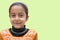 Cute young Indian girl with smiling pose on soft green backdrop, ample empty space for text
