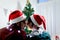 Cute young LGBT couple wearing Santa hat from behind kissing, sharing special moment together on Christmas holiday, gay male lover