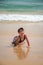 Cute young little girl laughing laying in a swimsuit in the sand on a beach.