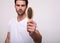 Cute young man holds a hairbrush directly to the camera