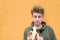 Cute young man looks at the stuffed banana in his arms. A student eats a banana on the background of an orange wall