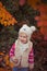 Cute young russian baby girl stylish dressed in warm white fur handmade jacket blue jeans boots and hooked hat teddy bear posing i