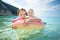 Cute young sisters floating on toy ring at Myrtos beach, the most famous and beautiful beach of Kefalonia, a large coast with