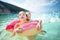 Cute young sisters floating on toy ring at Myrtos beach, the most famous and beautiful beach of Kefalonia, a large coast with