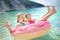Cute young sisters floating on toy ring at Myrtos beach, the most famous and beautiful beach of Kefalonia, a large coast with