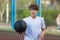 Cute young sporty boy in white t shirt plays basketball on his free time, holidays, summer day on the sports ground. Sport