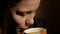 Cute young teenager girl is drinking coffee or tea at home. Closeup