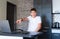 Cute young teenager in a white shirt sitting behind a desk in the kitchen next to laptop and study. Serious boy makes homework