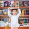Cute Young Toddler Standing and Holding Book in Head. Child in a Library, Shop,Bookstore.