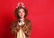 Cute  young woman in a Christmas reindeer costume dreamily looks up and makes a   wish on colorful red background