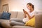 Cute young woman on a comfortable sofa using her cell phone