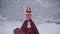 Cute young woman in fairy tale image in red royal dress with white violin stands on snow in winter forest