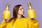 Cute young woman in fur sweater blowing sending air kiss hold halfs of fresh pineapple fruit isolated on violet pastel