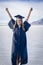 Cute Young woman in her graduation cap and gown showing excitement after graduating