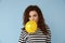 Cute young woman inflating balloon on color background