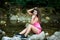 Cute young woman rests on a rock in river bed on late summer aft