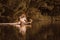 Cute young woman sitting by the lake touching water by her leg