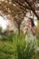 Cutelittle girl walk on the fresh air in the park. Kid blow dendelion. Arround flowering tree and green grass