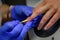Cuticle removal, close-up. Manicure in the salon. Manicurist in blue gloves shifts the cuticle of the nail with metal spatula