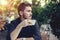 Cutie man with cup of coffee looking at mobile phone outdoors