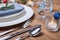 Cutlery, plates, napkin and Christmas decor on wooden table
