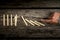 Cutout of a man holding up fallen dominoes as human hand pushes