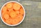 Cuts carrot in white bowl on wooden, table