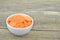 Cuts slices of carrot in bowl on wooden, closeup