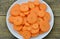 Cuts slices of carrot in plate on wooden