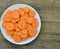 Cuts slices of carrot in plate on wooden