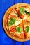 Cutted margherita pizza with basil on blue background