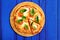 Cutted margherita pizza with basil on blue background with copyspace