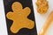 Cutted out gingerbread man on raw dough on black teflon baking sheet on the white background