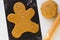 Cutted out gingerbread man on raw dough on black teflon baking sheet on the white background