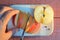 Cutting an apple with his hand with knife on cutting wooden cutting board on a red-brown background at sunset