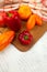 Cutting board with assort of different tomatoes and bell pepper on white wooden background