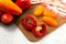 Cutting board with assort of different tomatoes and bell pepper on white wooden background