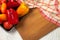 Cutting board with assort of different tomatoes and bell pepper on white wooden background