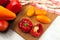 Cutting board with assort of different tomatoes and bell pepper on white wooden background