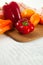 Cutting board with assort of different tomatoes and bell pepper on white wooden background