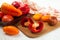 Cutting board with assort of different tomatoes and bell pepper on white wooden background