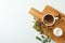 Cutting board with cup of fresh coffee, milk, coffee beans and plant branch on white background, space for text