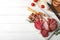 Cutting board with different sliced meat products on wooden background, flat lay.