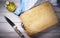 Cutting board, knife, cruet, extra virgin olive oil and dish towel on wooden background.