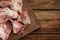 Cutting board with raw chopped meaty bones on wooden table, top view. Space for text