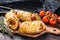 Cutting board with sausage rolls in the dough. Dark wooden background. Top view