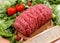 The cutting board on wooden ground beef, tomatoes, peppers, greens