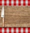 Cutting breadboard and kitchen knife. Cooking set over red gingham tablecloth.